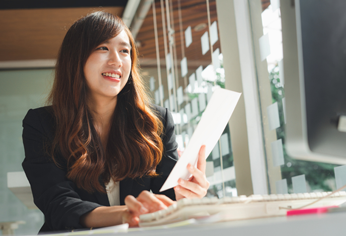 Asian female finance worker holding papers and smiling happily