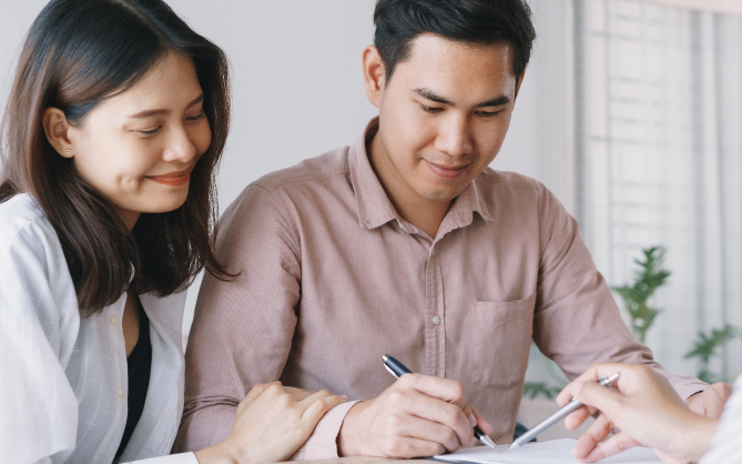 Happy couple signing on a loan contract from the top licensed money lender in Orchard, Singapore